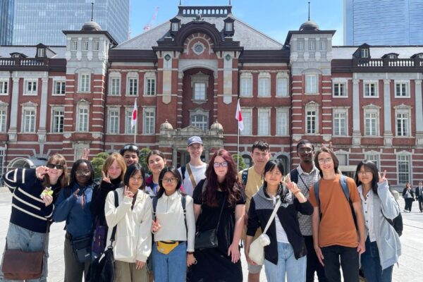 10 Students posing for photo in front of historic house in Japan