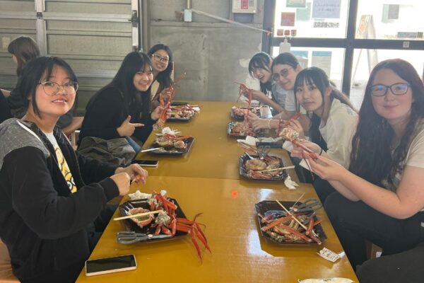 2 Students smiling whilst eating crab in Japan